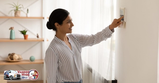 A woman holding her finger up to a wall thermostat